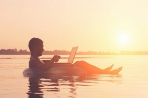 Guy floating with laptop guy on laptop beach