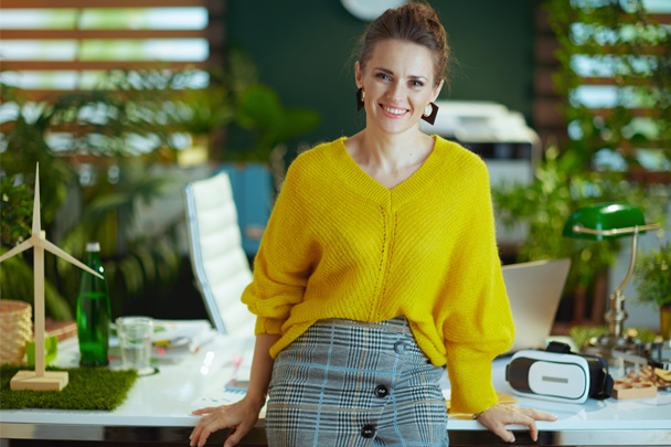 professional leaning on desk in plant filled office